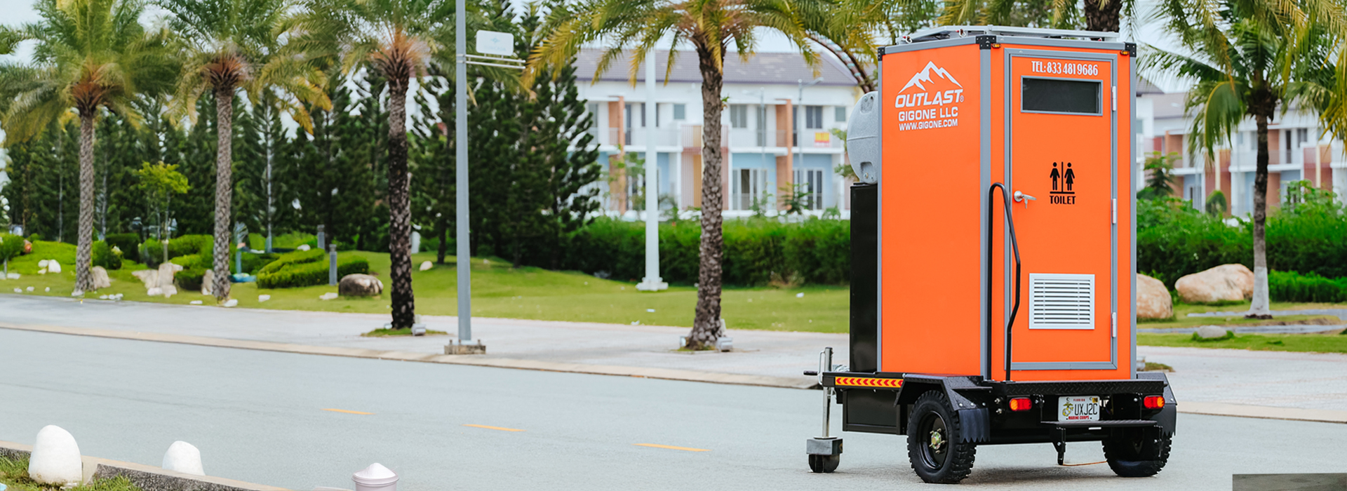 Bright orange portable toilet trailer on roadside