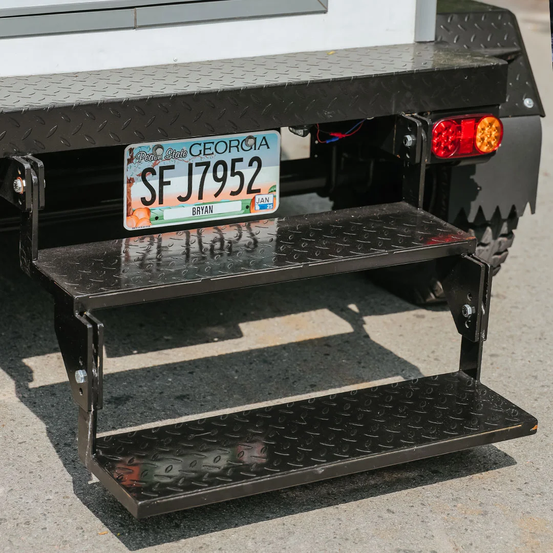 Georgia registration plate on the rear of a restroom trailer, showing a valid plate and tail lights as part of a registration-ready unit